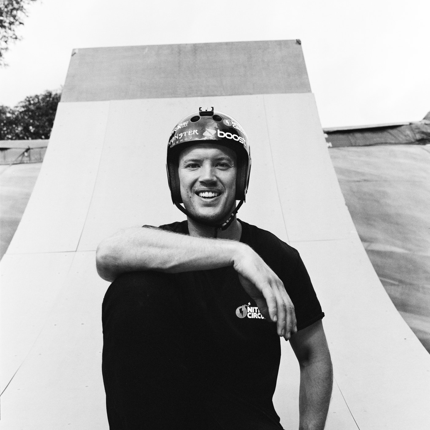 Ryan Williams in a helmet, grinning, arm resting on his knee at the foot of a huge ramp.