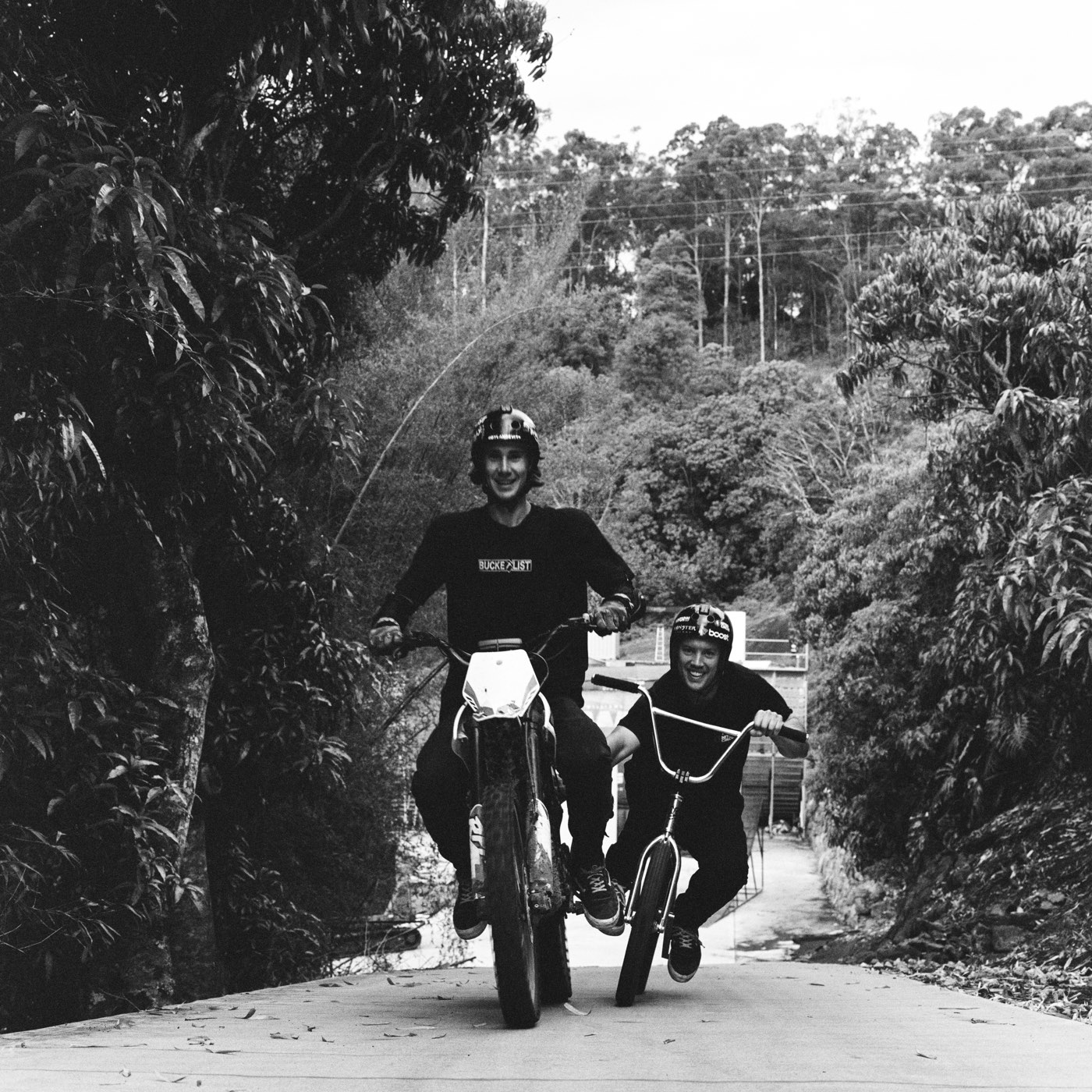 Two riders charging down the driveway side by side, grinning.