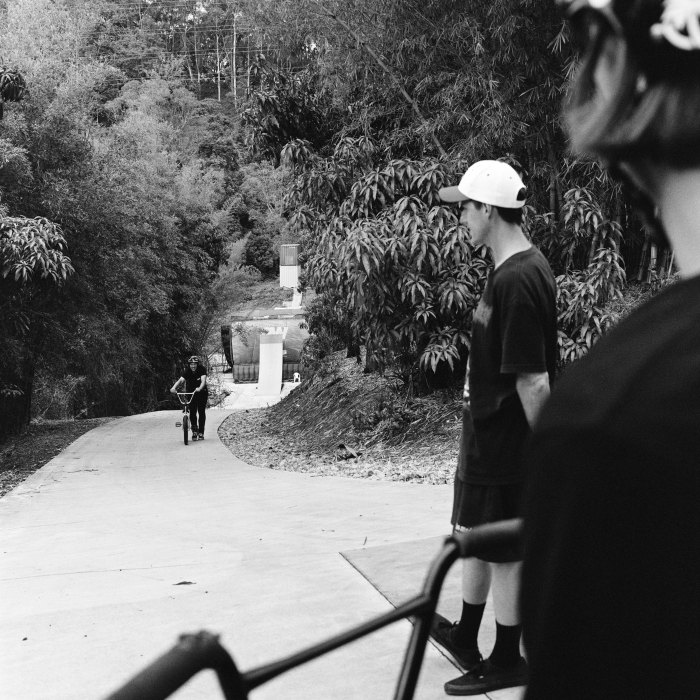 Mike in a white cap watching from the side as Ryan rolls in down the driveway.